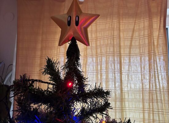 Weihnachtsbaum-Spitze in der Form eines Mario-Sternes, auf dem Baum
