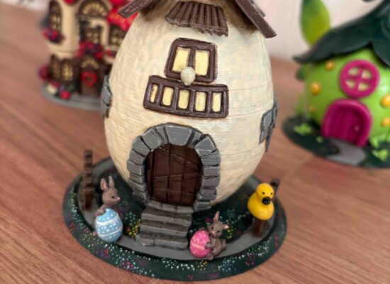 Das Zuhause des Osterhasen ist ein Ei, mit kleinen Fenstern, Dach und bemalten Eiern im Garten