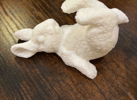 Osterhase in weiß, auf dem Rücken liegend, strampelnd